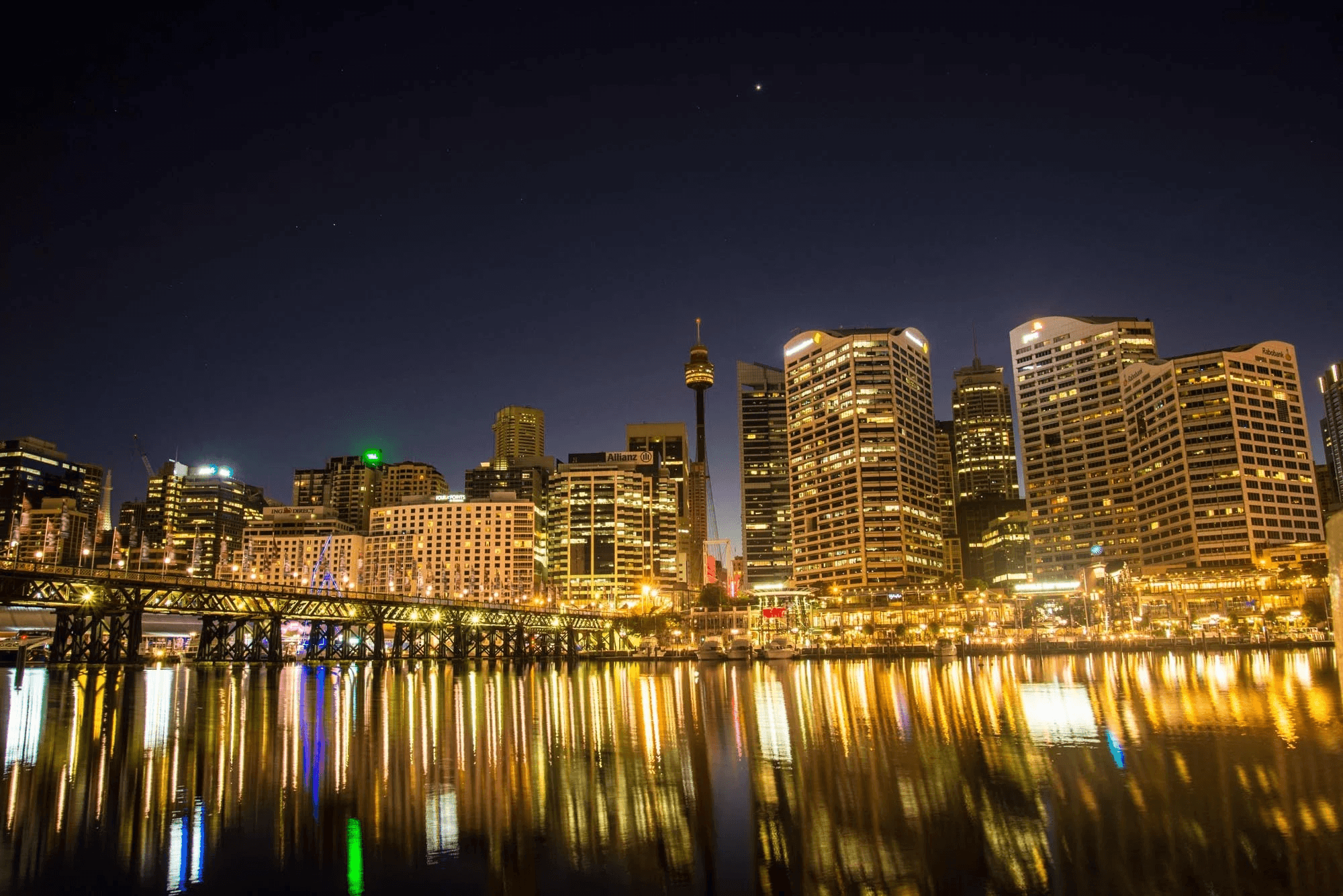 Illuminated Sydney skyline and Sydney Tower Eye reflected over Darling Harbour at night