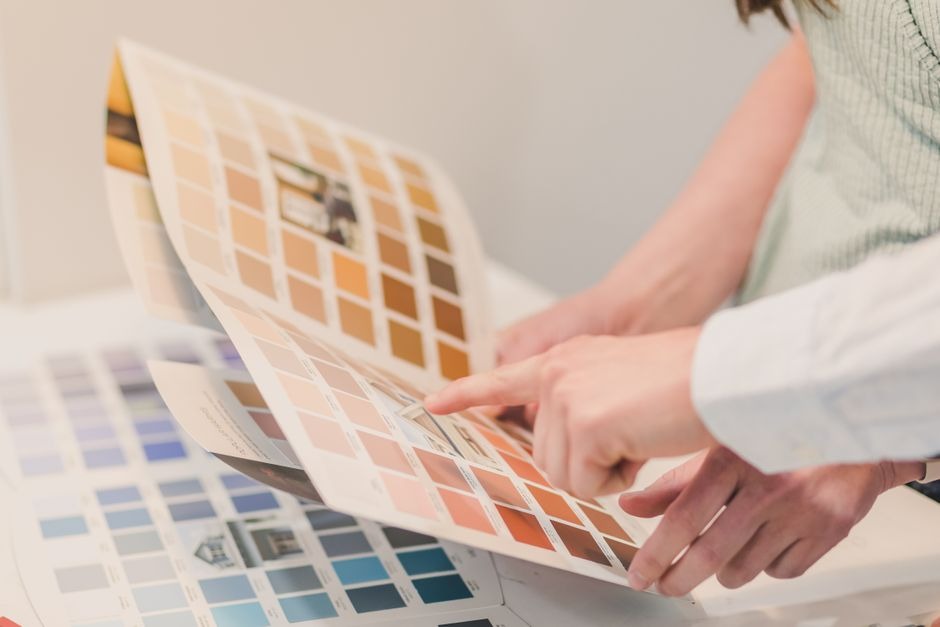 Two people comparing paint colour swatches from a sample brochure to choose a finish
